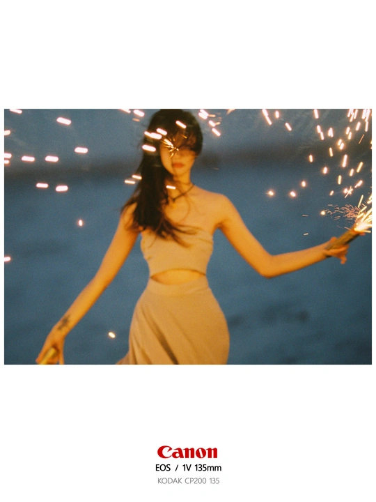 一个穿着连衣裙、戴着墨镜、撑着雨伞的女人站在海滩上