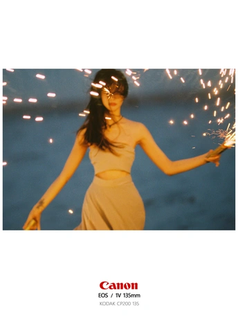 一个穿着连衣裙、戴着墨镜、撑着雨伞的女人站在海滩上