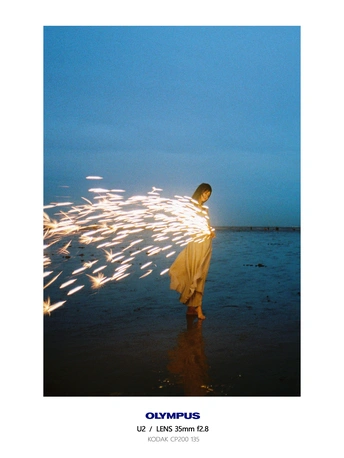 当一个男孩沿着海滩散步时 一个穿着连衣裙的年轻女孩站在水中