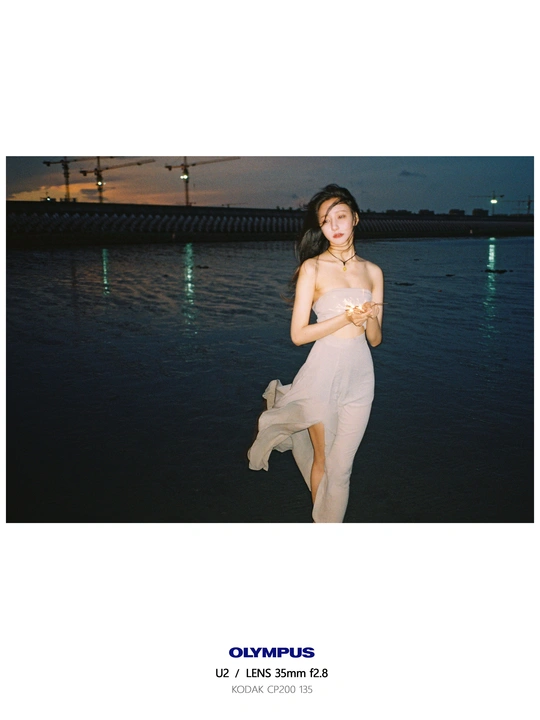 一个穿着白色连衣裙的女人站在水体旁边