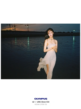 一个穿着白色连衣裙的女人站在水体旁边