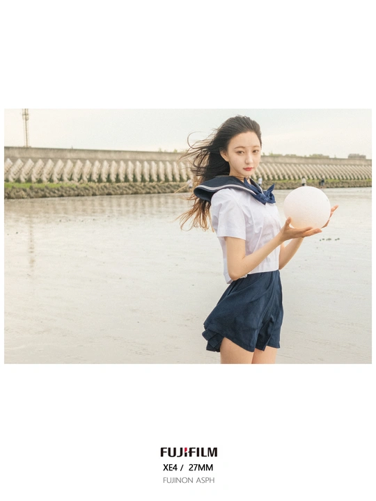 一个穿着校服拿着白色球的年轻女子站在河边