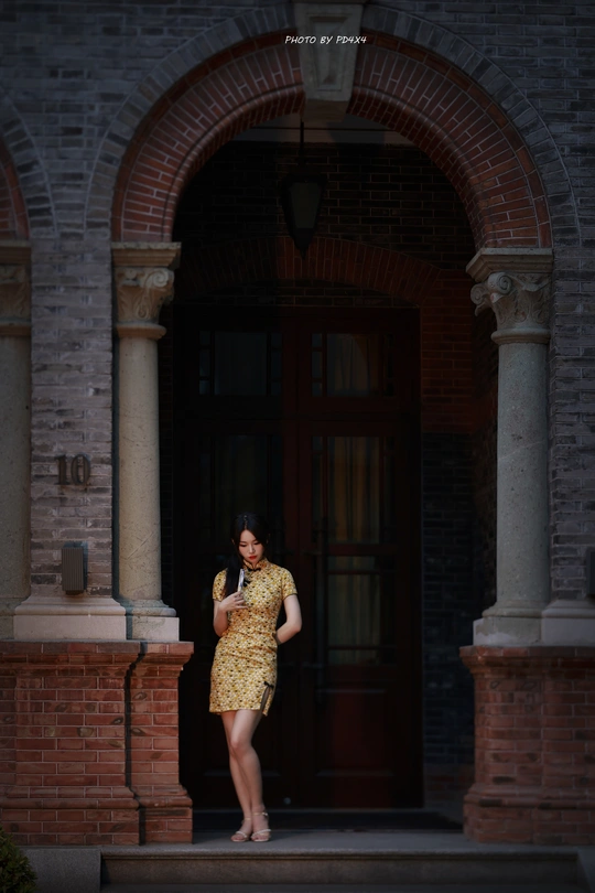 一个穿着黄色连衣裙的女人站在一栋楼的门前