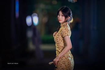 一个穿着黄色连衣裙的年轻女子撑着雨伞走在街上