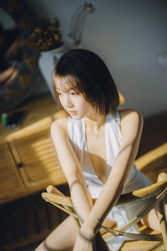 一位年轻女子坐在木椅上摆姿势