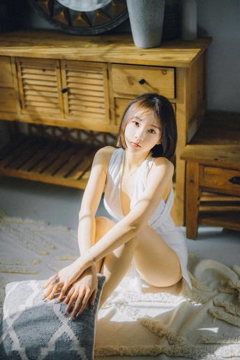 一个年轻女子坐在地板上的一块白毛巾上