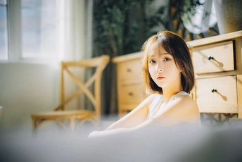 一个年轻女子坐在床上 正在看笔记本电脑 而一个小女孩则躺在房间里。