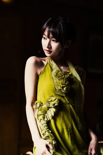 一位穿着黄色连衣裙站在黑暗地方的女人