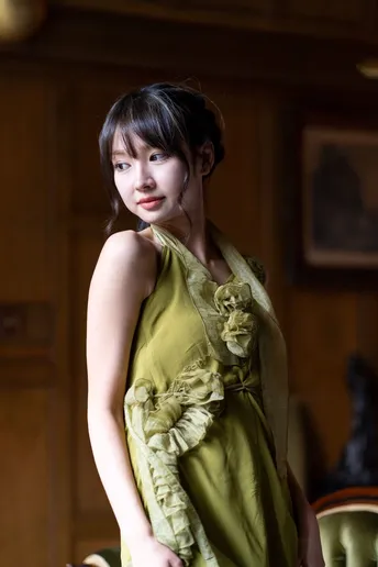 一位穿着绿色连衣裙的年轻女子站在一个古董客厅里