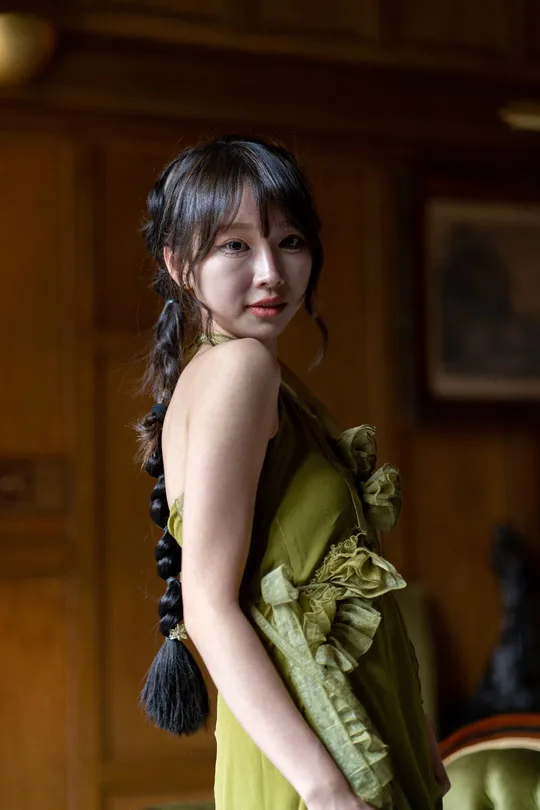 一位穿着绿色连衣裙的年轻女子站在一个古董客厅里