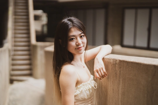 一位美丽的年轻女子穿着白色连衣裙 倚靠在墙上