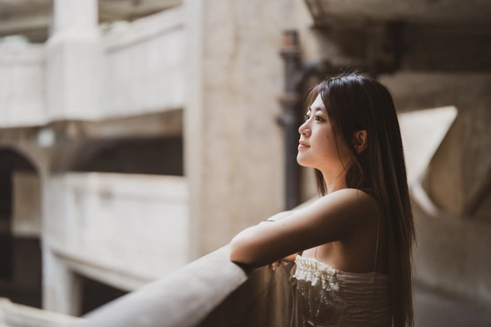 一位穿着美丽裙子的年轻女子靠在建筑物的栏杆上