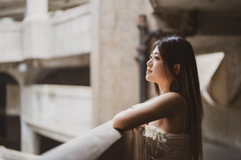 一位穿着美丽裙子的年轻女子靠在建筑物的栏杆上