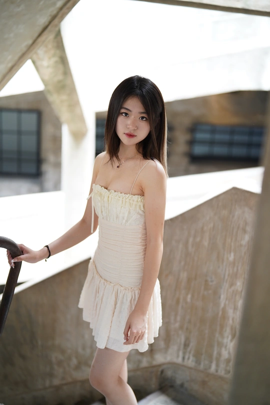 一位穿着白色连衣裙的年轻女子站在楼梯上 手里拿着一把雨伞。