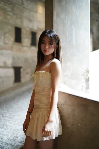 一个穿着黄色连衣裙的年轻女子站在一座废弃的建筑中