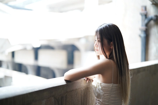 一位美丽的年轻女子穿着白色连衣裙 倚靠在窗户旁
