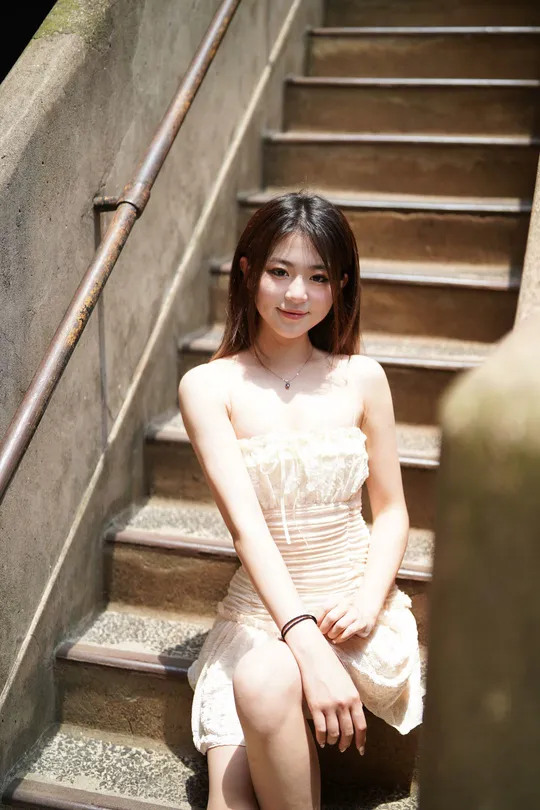 一个穿着白色连衣裙的年轻女子坐在一些楼梯上