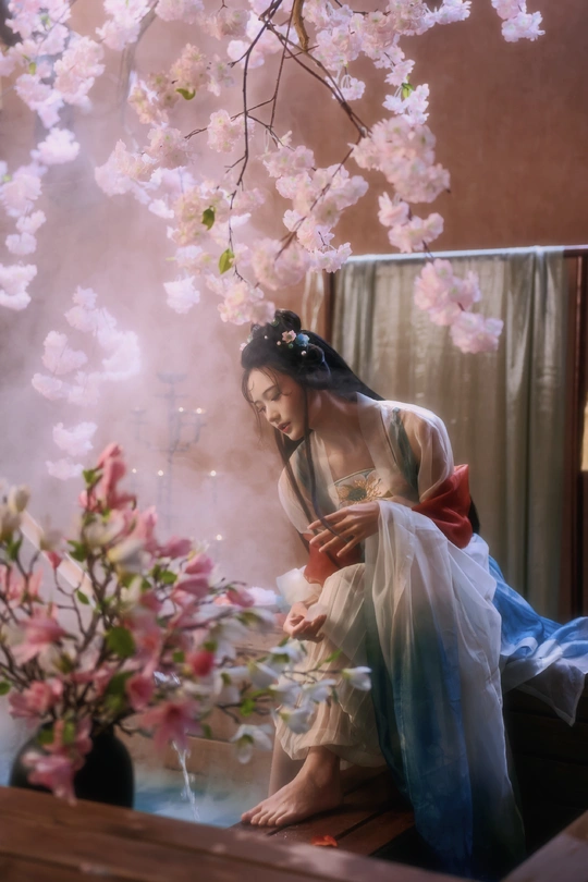 一幅女人坐在树下的画 旁边有一个插满花的花瓶。