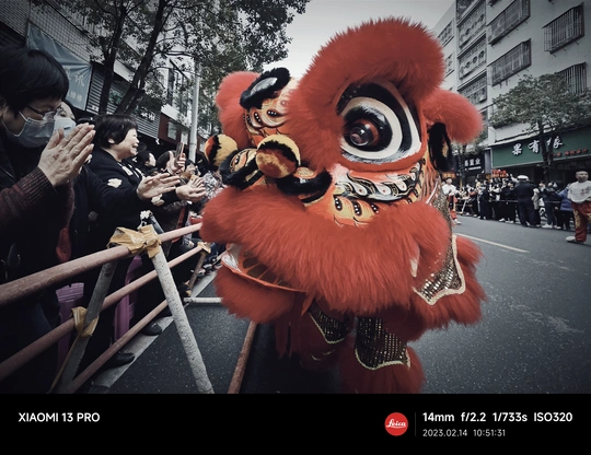一个戴红面具的人在参加游行的人群中 后面跟着一群穿 costume 的人。