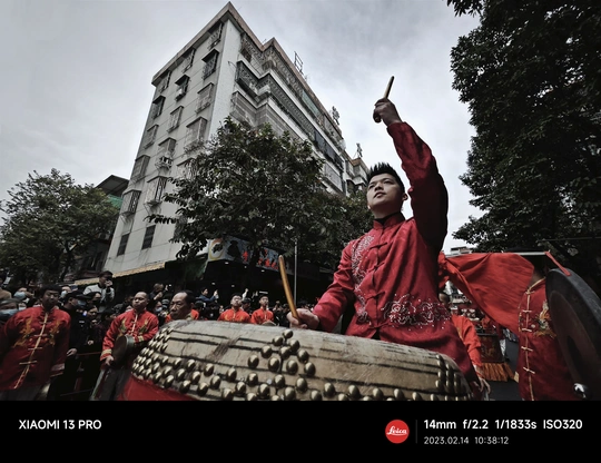 一位穿着红衣服的人在街头的节日上表演传统鼓。