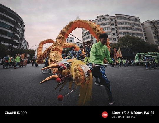 一群人沿着街道走 后面跟着一条巨大的龙。