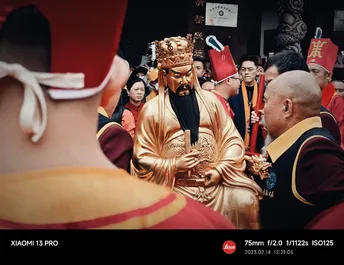 一个穿着金色长袍的男人 背景有一个雕像。