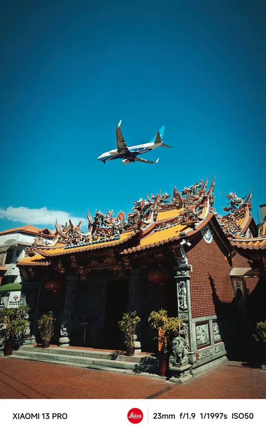 飞机在蓝天上飞过一座建筑物