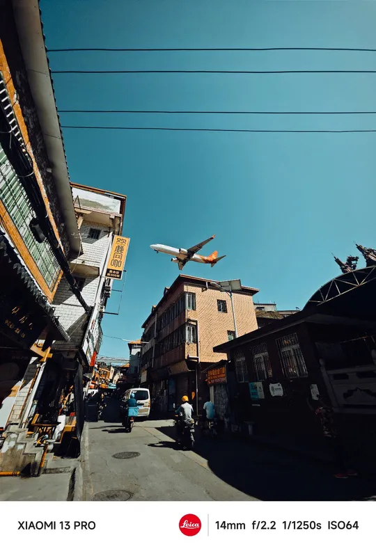 天空上飞行的飞机 上方有建筑物和人。