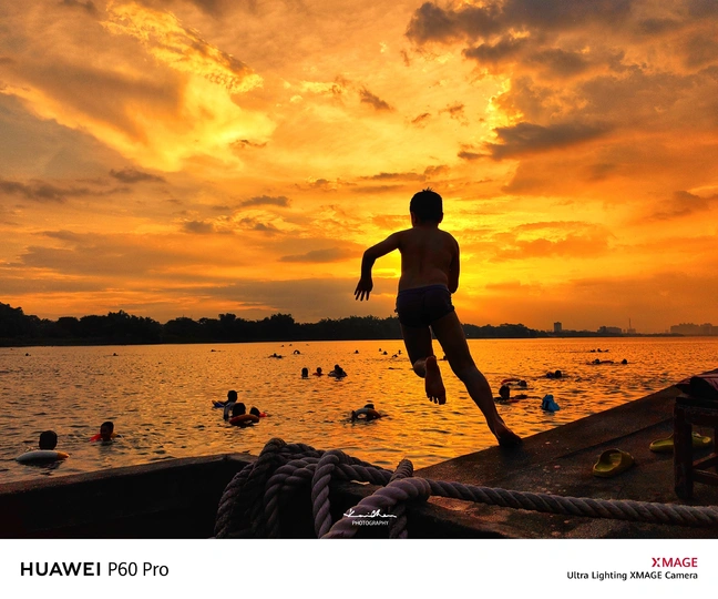 一个年轻男孩在日落时从船上跳入水中