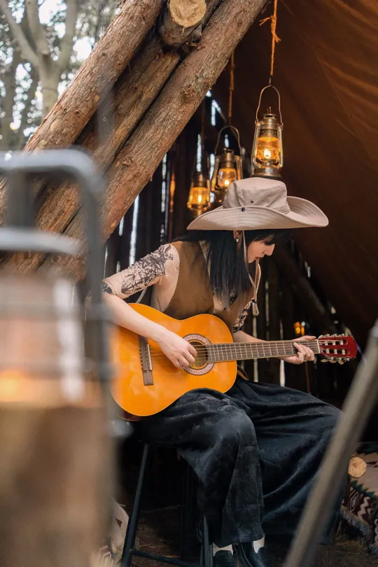 一个戴帽子的人在帐篷里弹吉他