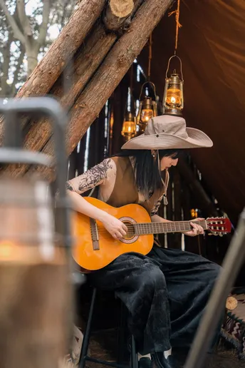 一个戴帽子的人在帐篷里弹吉他
