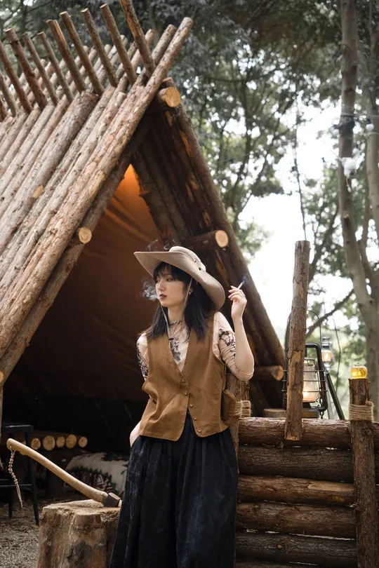 一个戴黑色连衣裙和帽子站在帐篷外面的女人