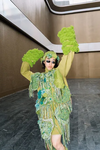 一位穿着绿色服装的女士参加了时装表演。