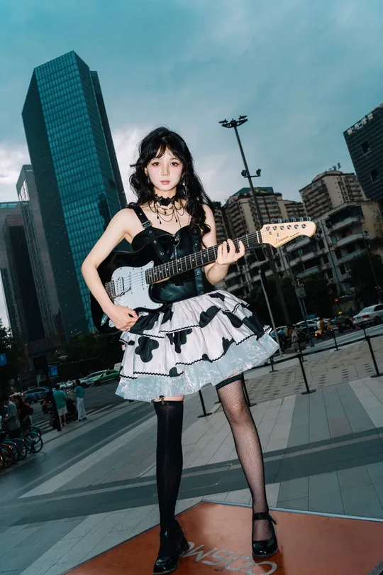 一位穿着连衣裙的年轻女子在城市中弹吉他