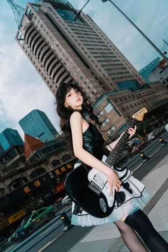 一个穿着黑色连衣裙的年轻女子抱着一把吉他