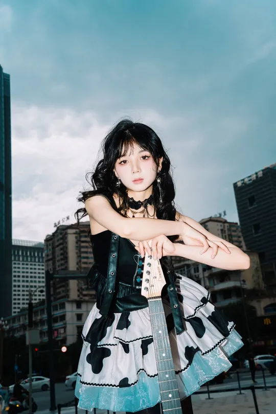 城市屋顶上的穿连衣裙的女人带着吉他