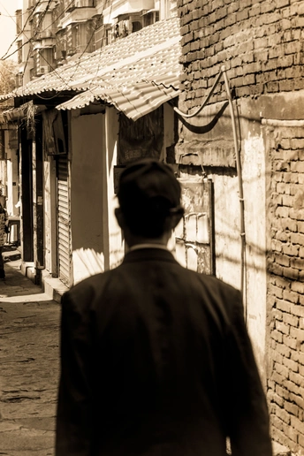 沿着老建筑旁边的小巷走的男人