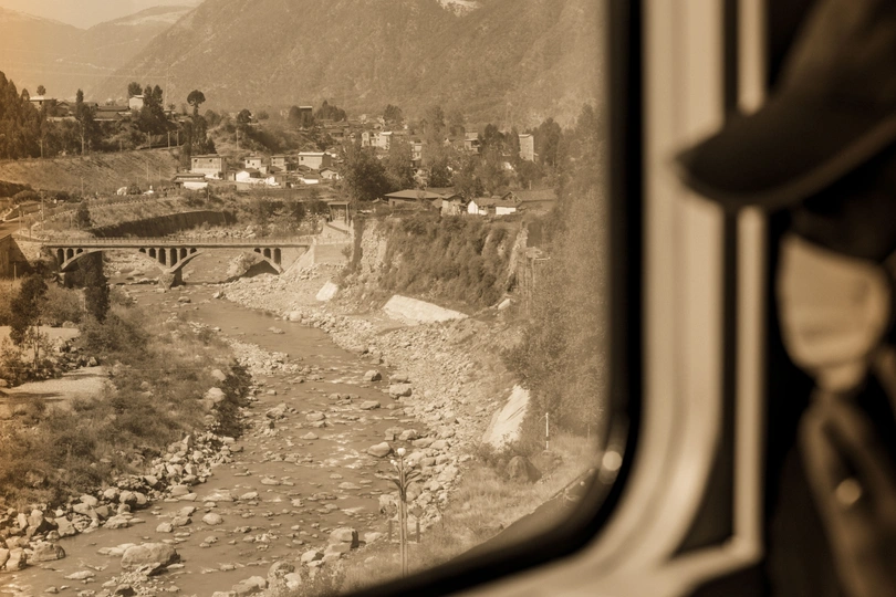 从火车窗户拍摄的黑白照片 展示了河流、山脉和城镇。