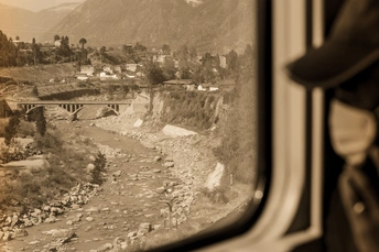 从火车窗户拍摄的黑白照片 展示了河流、山脉和城镇。