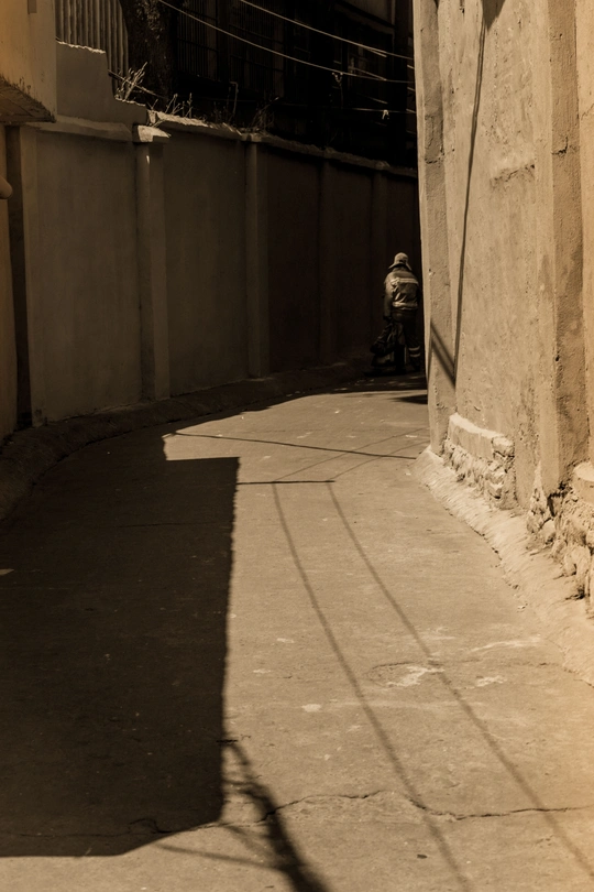 一条狭窄的巷子 一个人坐在椅子上沿着街道走。