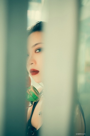 一位涂着绿色口红的年轻女子正在镜子前照看自己的脸。