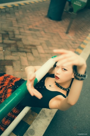 一位年轻女子坐在街上的绿色长凳上