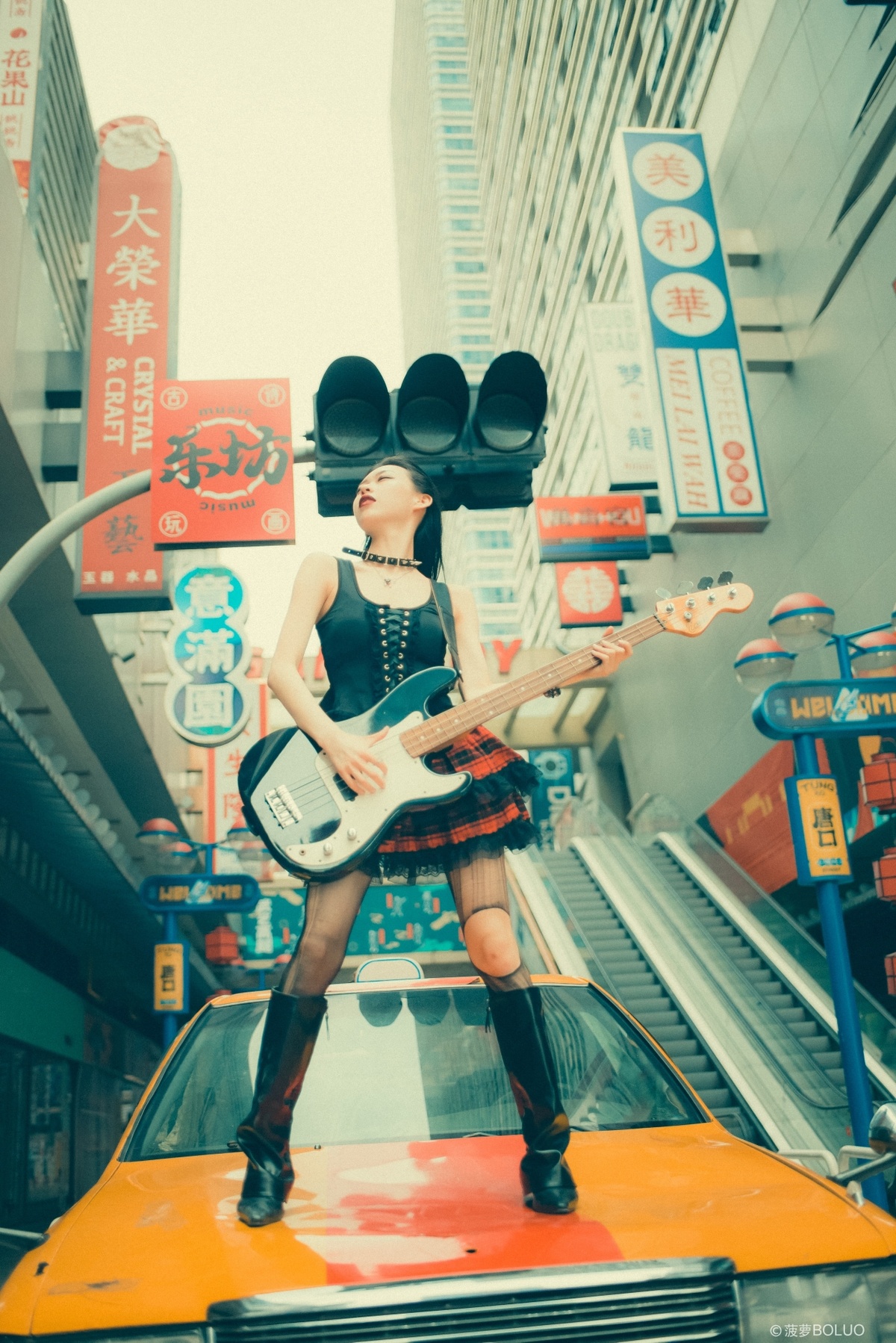 一位站在繁忙街道旁 靠近汽车 手里拿着吉他的女人站在自动扶梯上。