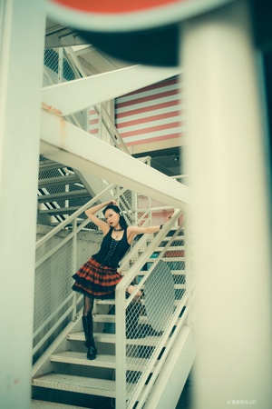 一个穿着连衣裙的年轻女子站在一些楼梯上