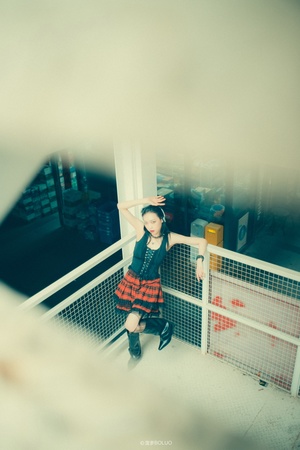 一个小女孩站在阳台上 头伸出建筑物的围栏之外。