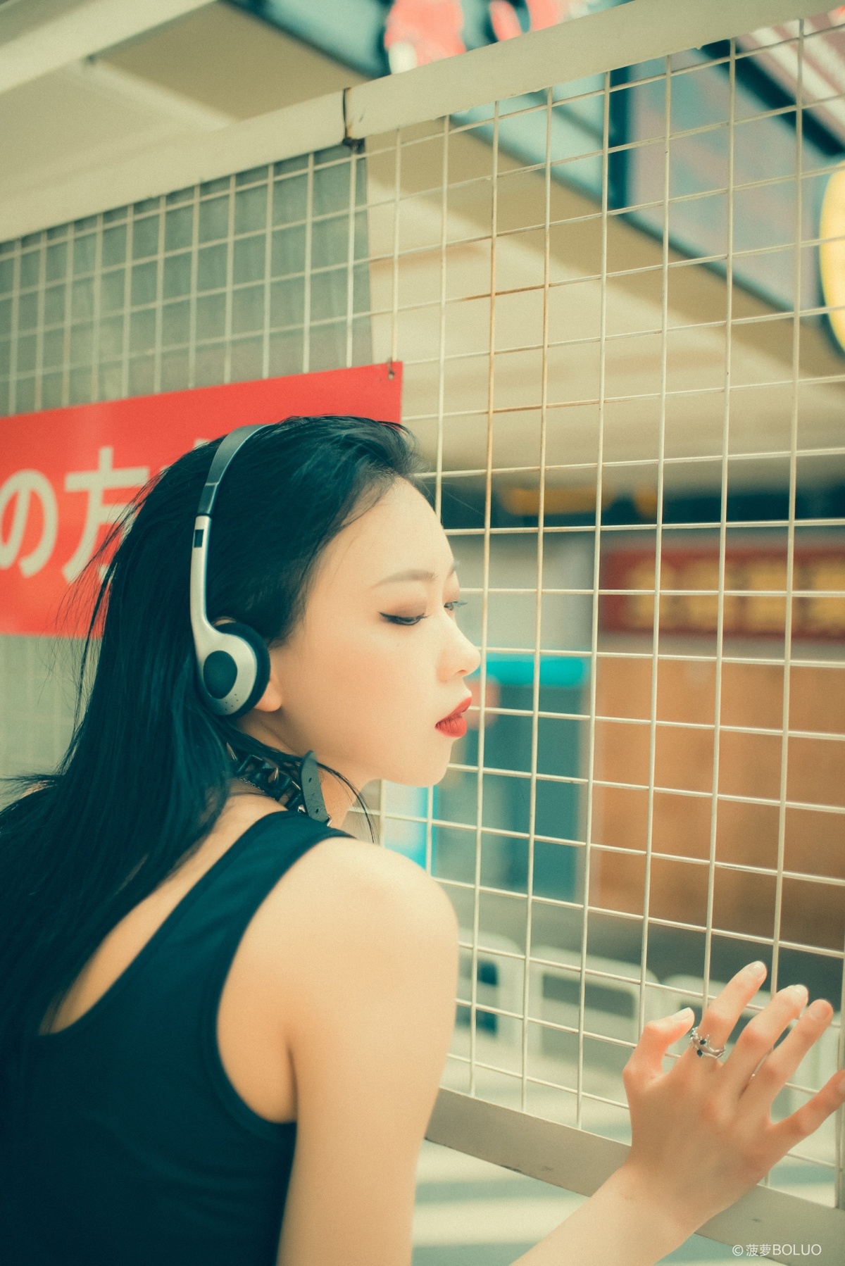 一位年轻女子戴着黑色耳机站在地铁站 同时听音乐并抽烟。