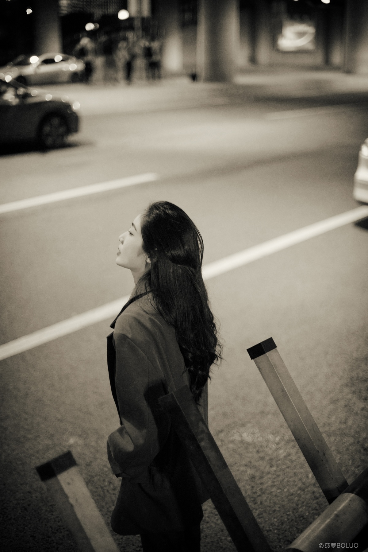 一个年轻女子晚上在街上带着行李箱站在马路中间。