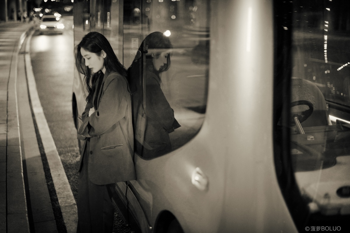 一张黑白照片 一位女子站在夜晚的火车旁边