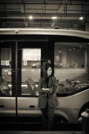 一张黑白照片 一位女士站在一列火车前