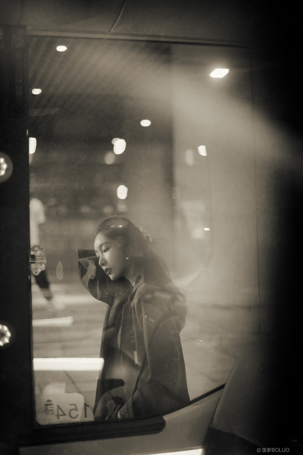 一位年轻女孩在夜晚的公交车镜子前看手机